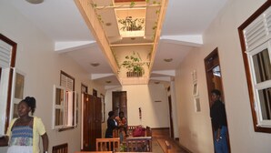 Pasillo de hotel con un atrio central, bancos de madera y plantas en macetas.