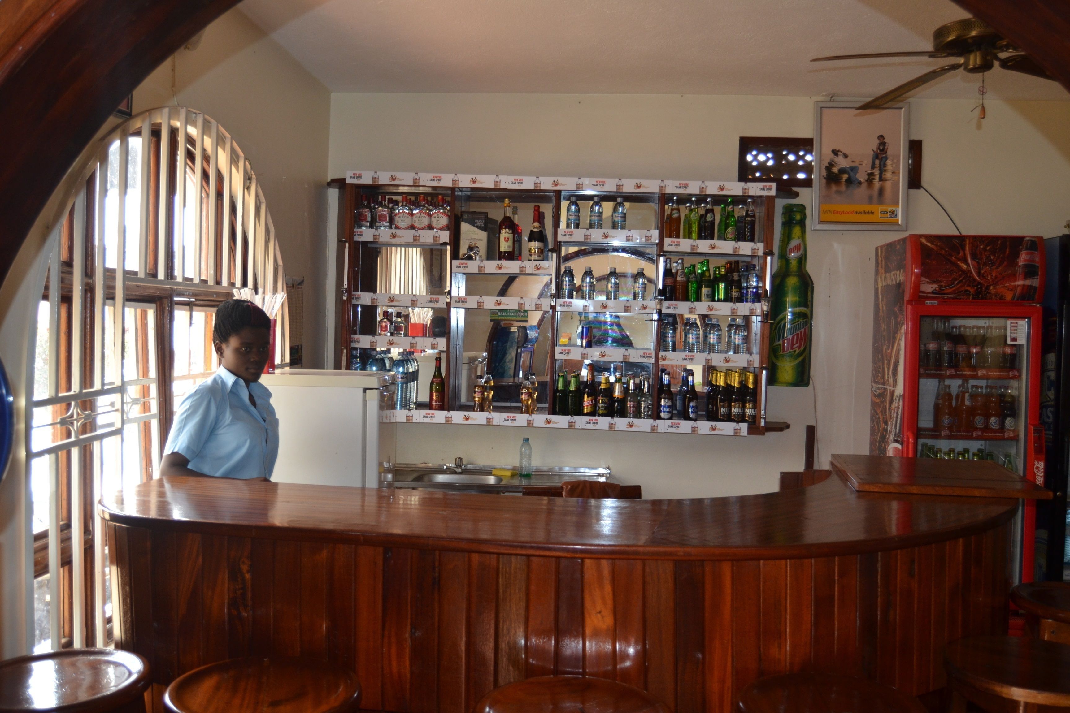 A bar area with wooden counters and shelves stocked with various bottles.