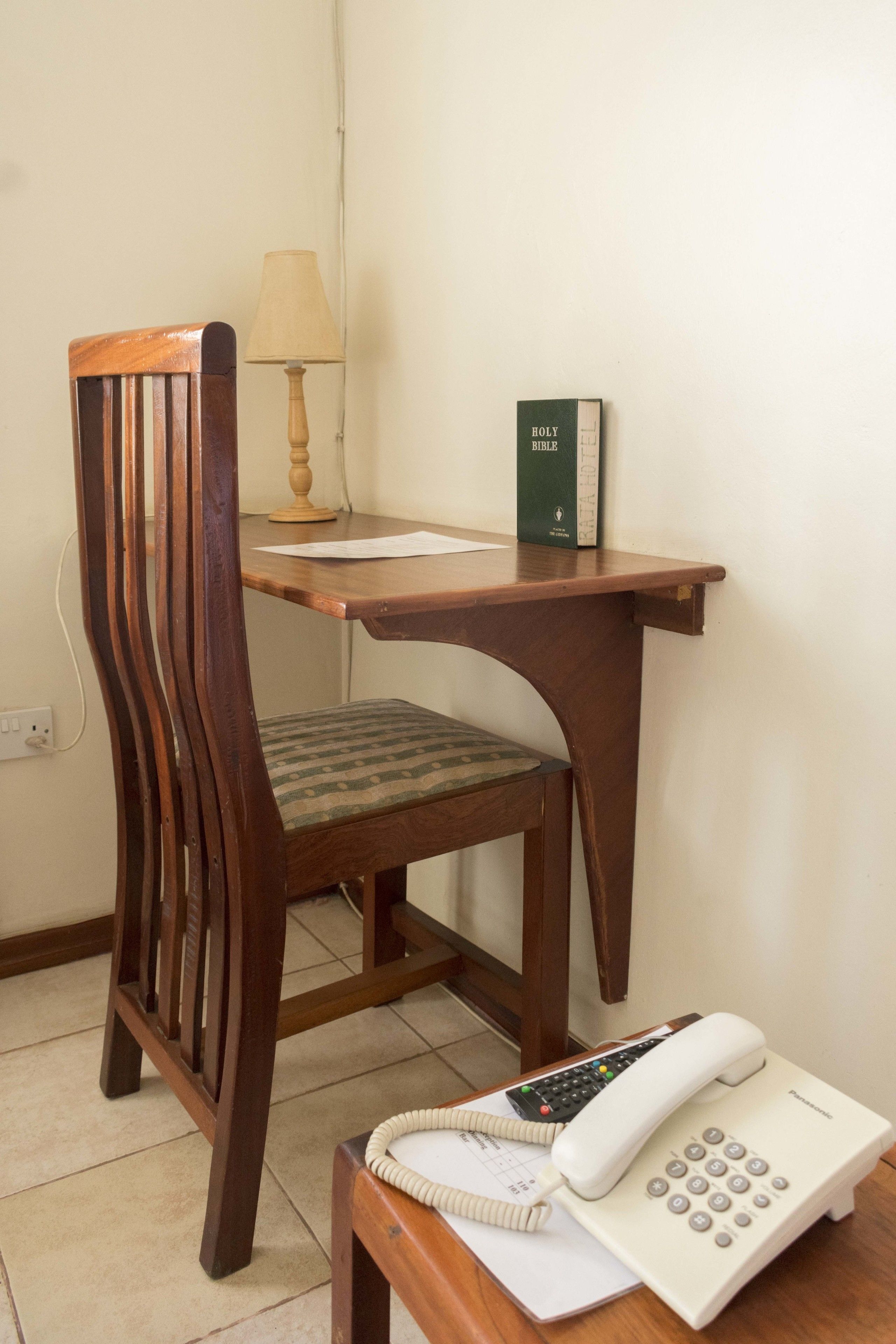A wooden desk with a telephone, a lamp, and a book.