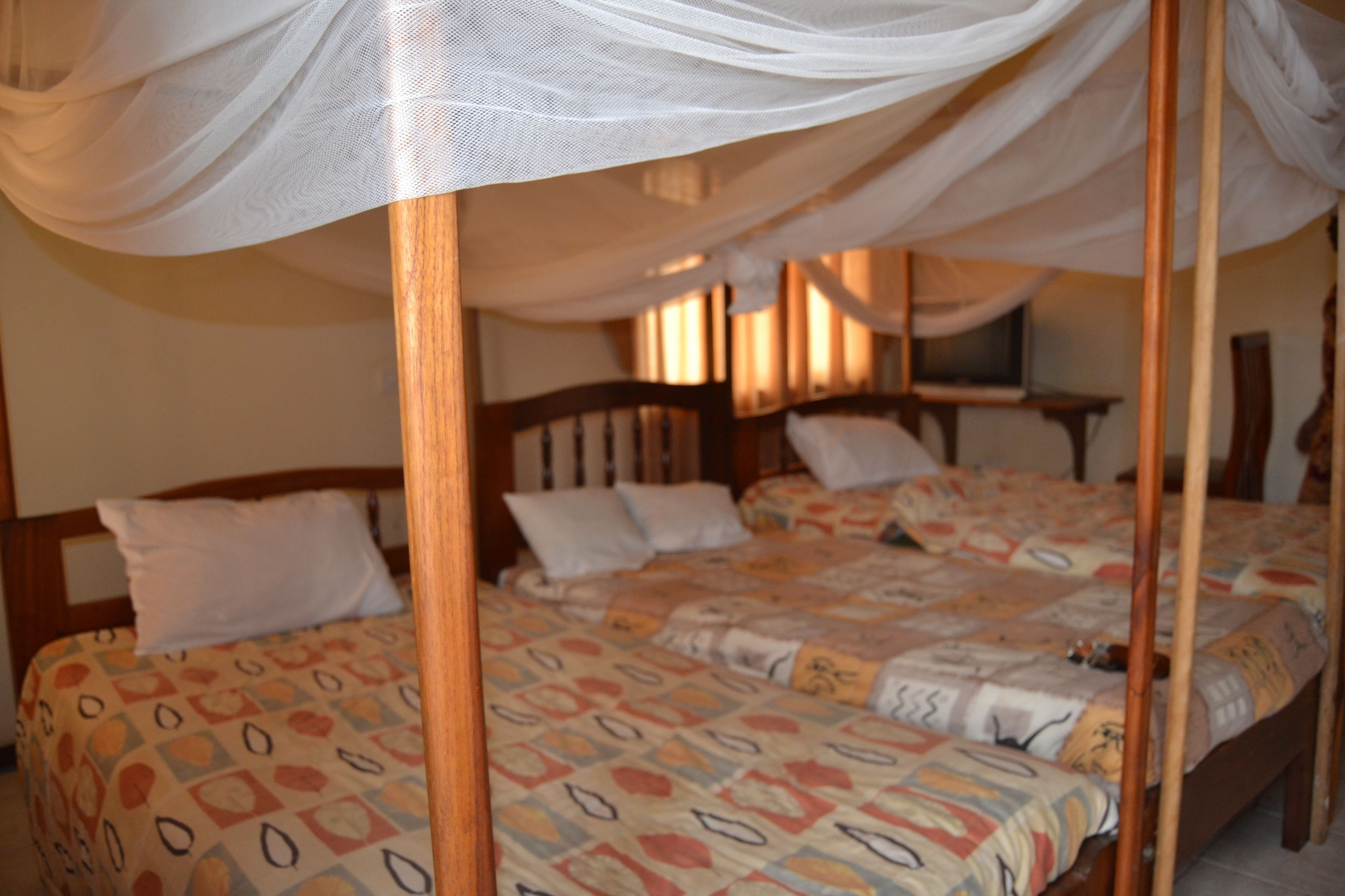 A bedroom with a four-poster bed, a patterned bedspread, and a canopy.
