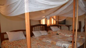 A bedroom with a four-poster bed, a patterned bedspread, and a canopy.