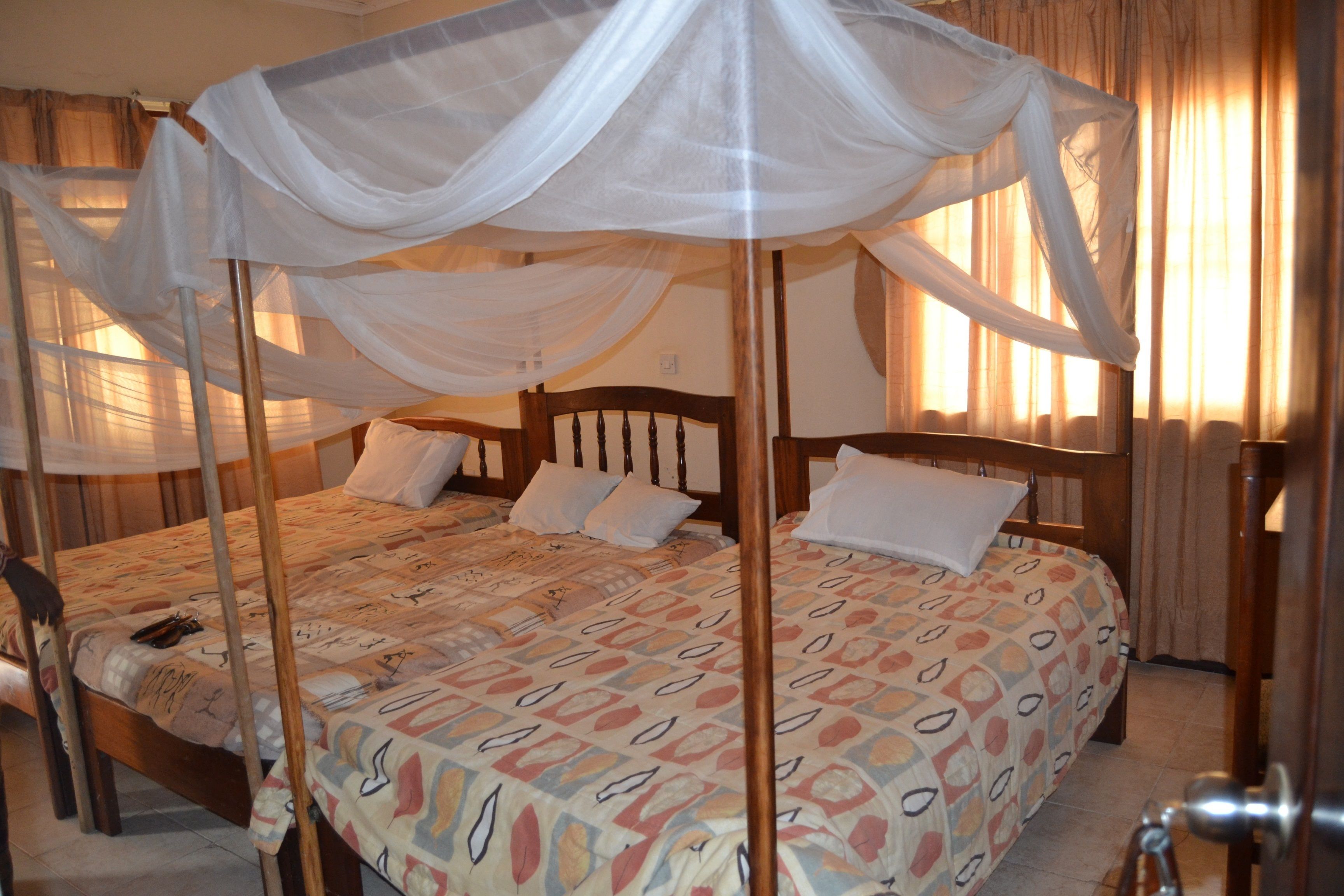 A four-poster bed with a canopy, wooden headboard, and patterned bedding.
