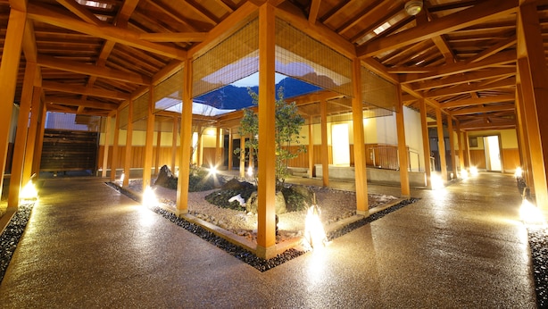 A covered walkway with wooden beams and a central garden area with rocks and a tree. - Fugetsugyosho (Toyooka)