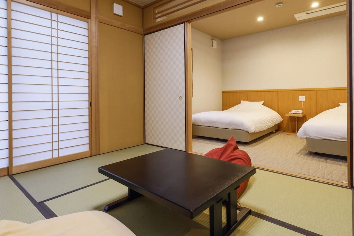 Um quarto japonês tradicional com tatames, uma mesa baixa e duas camas.