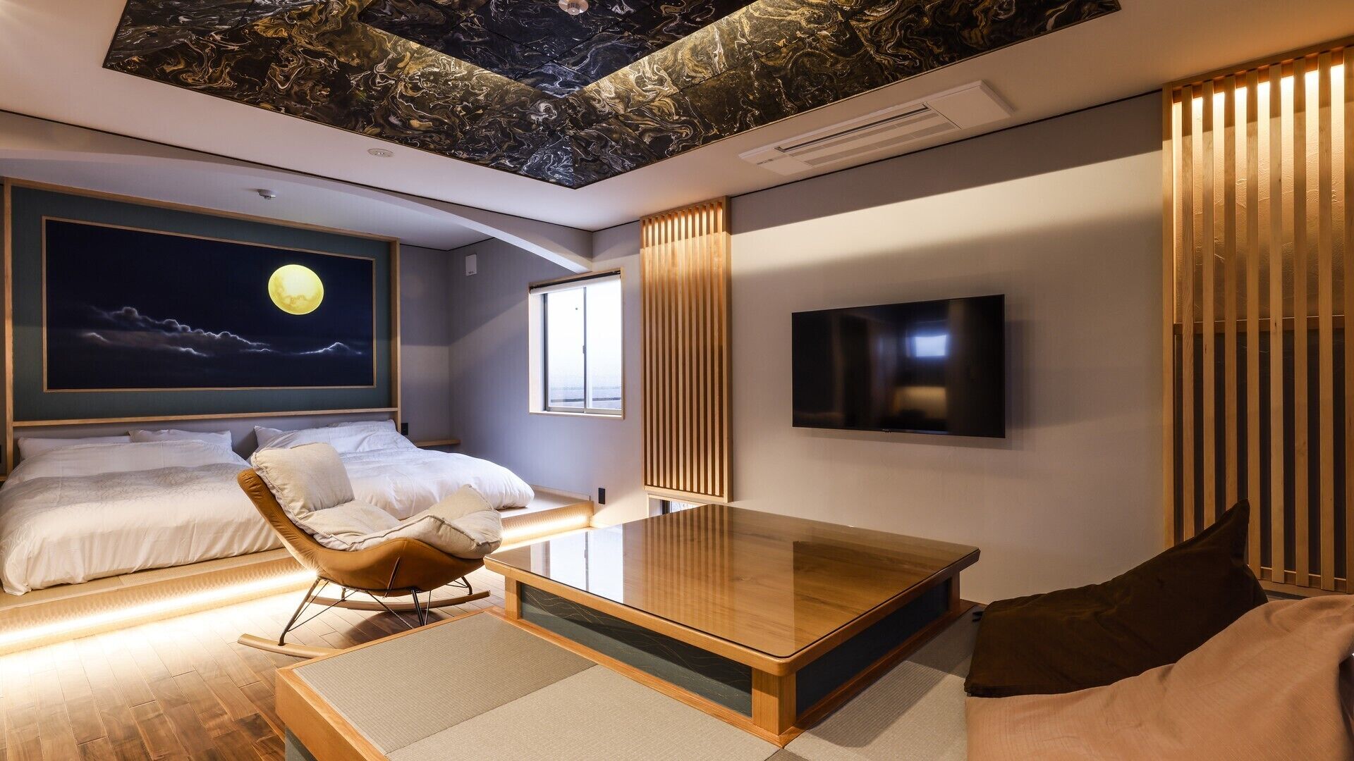 A modern hotel room with a bed, a sofa, a coffee table, a TV, and a ceiling with a marble-like design.