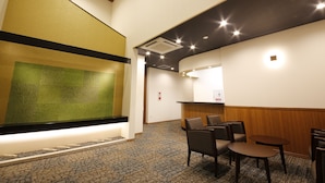 A hotel lobby with a reception desk, seating area, and a decorative wall. - Fugetsugyosho (Toyooka)