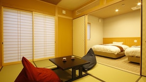 A traditional Japanese room with tatami flooring, a low table with two cups, and a bed with pillows. - Fugetsugyosho (Toyooka)