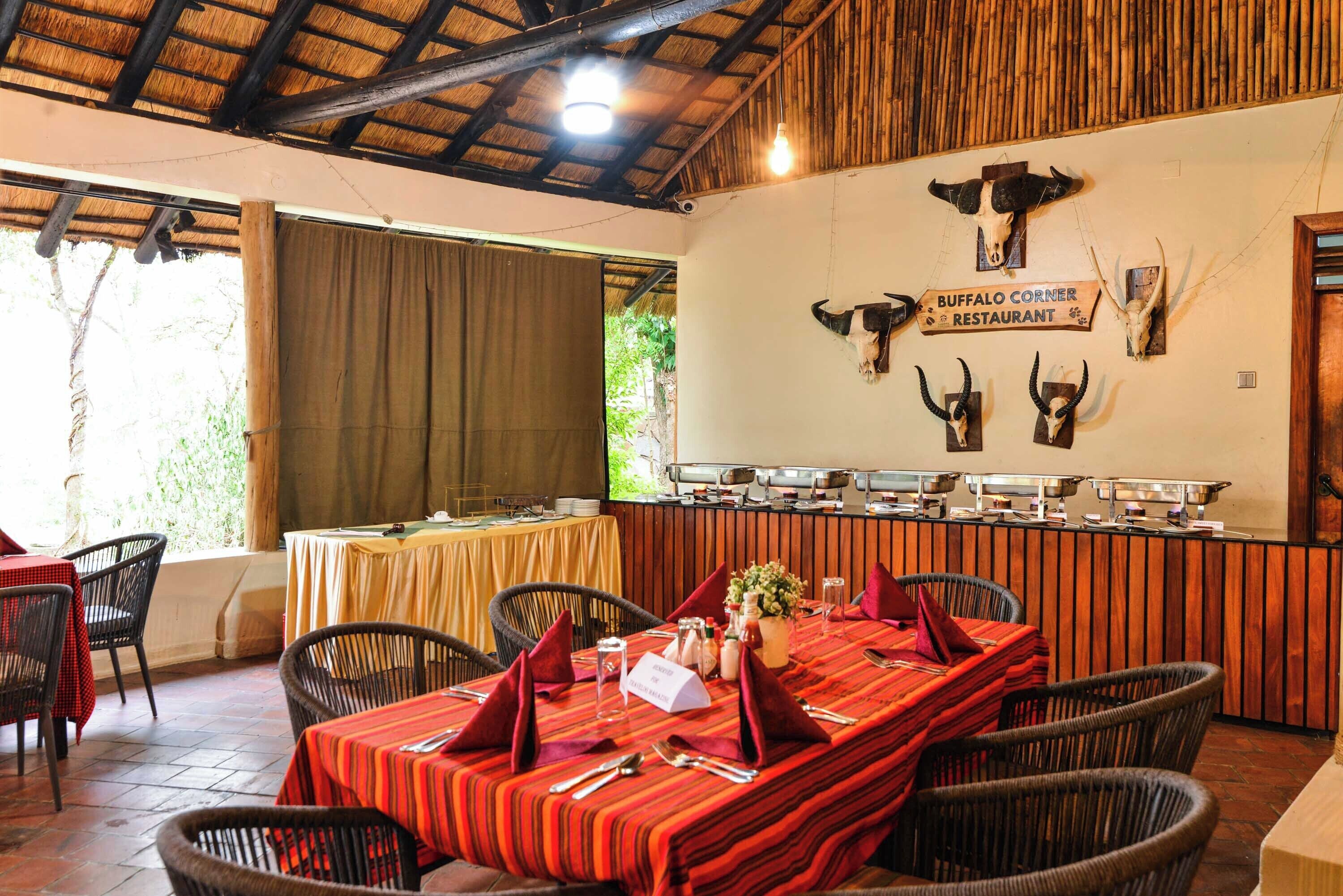 A restaurant with a thatched roof, wooden beams, and a buffet counter.