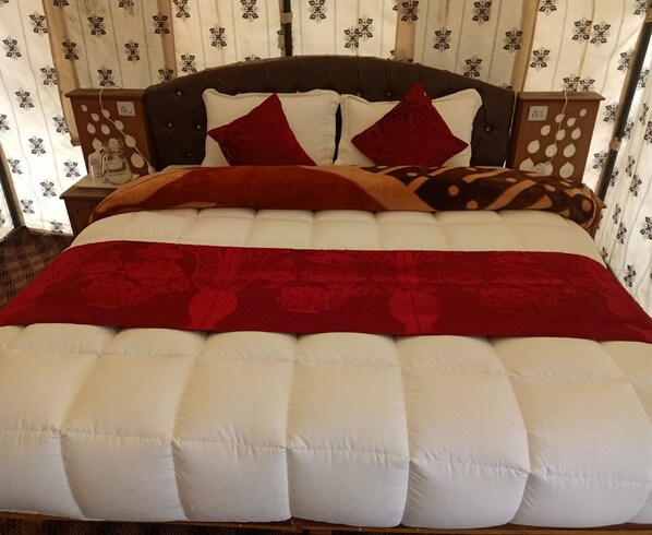 A bed with a white and red quilt, a brown headboard, and patterned curtains.