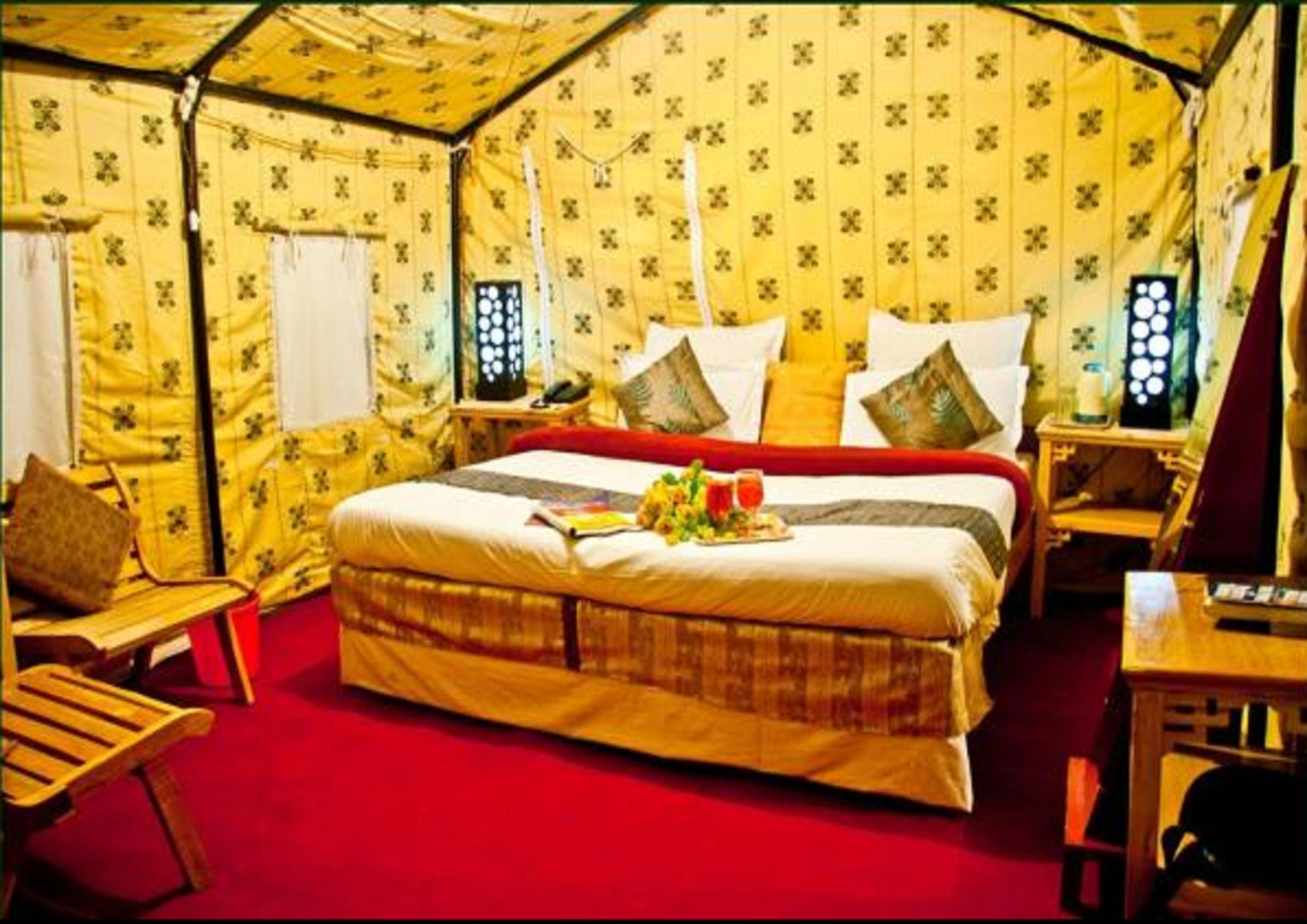 A tent-style room with a bed, wooden furniture, and a red carpet.