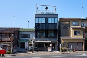 A hotel with a modern design, featuring a prominent entrance, a visible staircase, and a signboard. - Hotel Material (Kyoto)
