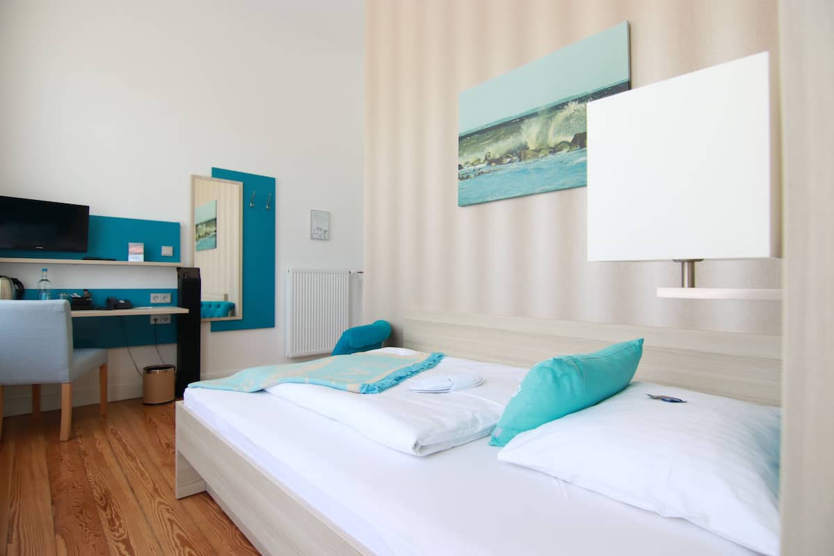 Een hotelkamer met een bed, een bureau, een stoel en een televisie.