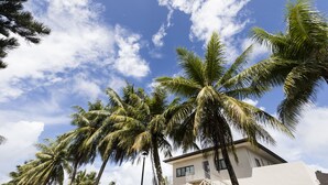 A modern building with a white exterior and a staircase leading to a balcony. - Pacific Palm Resort (Saipan)