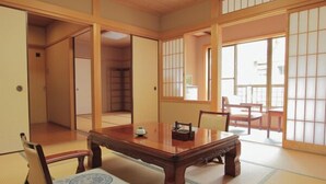 A traditional Japanese room with tatami flooring, a low wooden table, and sliding doors. - Okesho Ryokan (Toyooka)