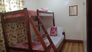 Uma cama beliche com estrutura de madeira, cortinas com padrão floral e chão quadriculado.