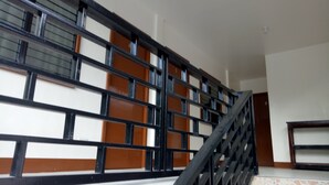 Uma escada com corrimão preto e paredes brancas, com painéis marrons e pretos.