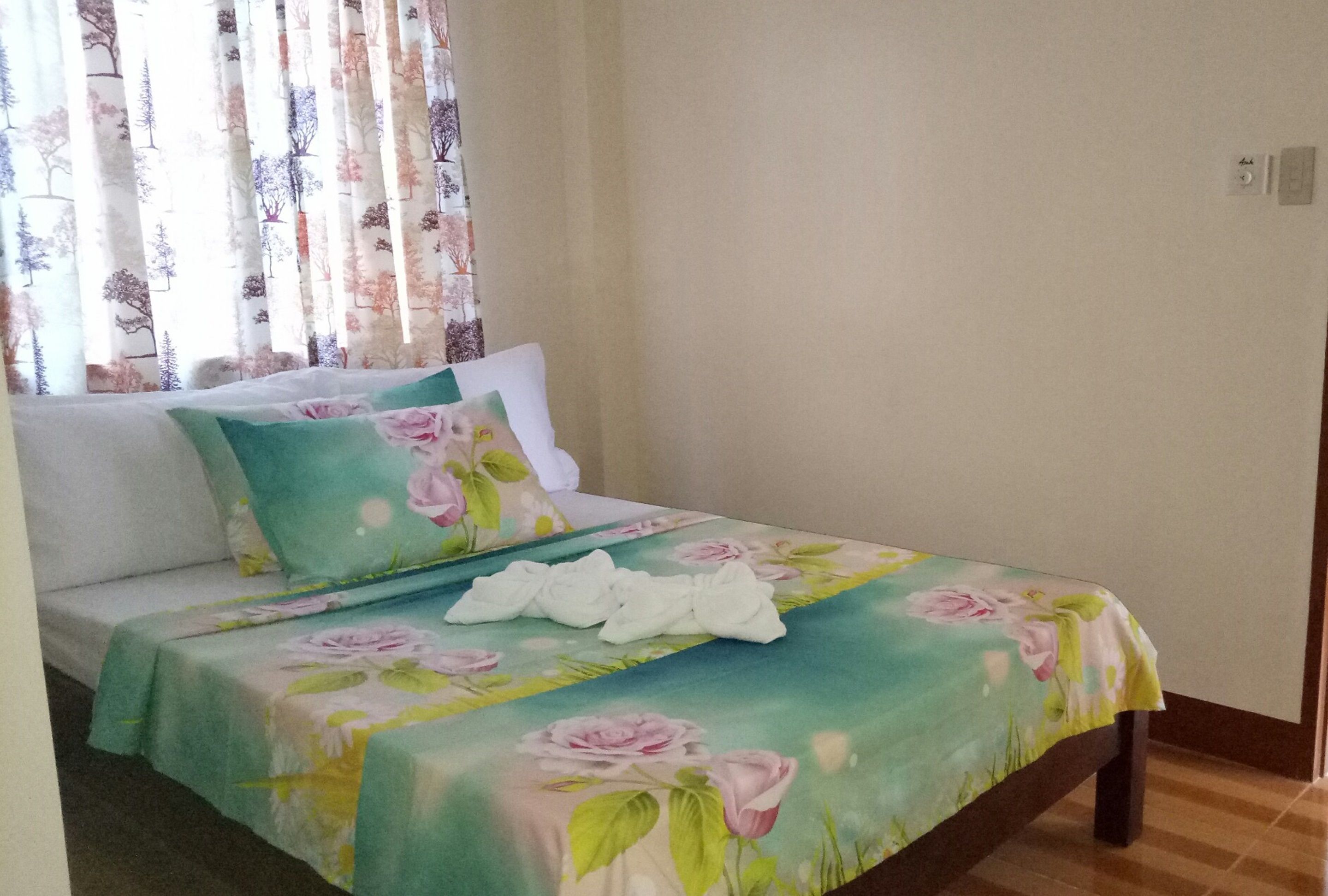 A bed with floral bedding, a white pillow, and a bedside table with a white cloth.