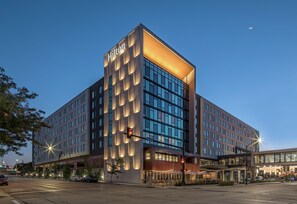 A modern hotel with a prominent 'Hilton' sign, large windows, and a well-lit entrance area. - Hilton Des Moines Downtown (Des Moines)