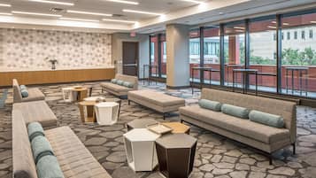 A hotel lobby with seating areas, a patterned wall, and large windows offering a view outside.