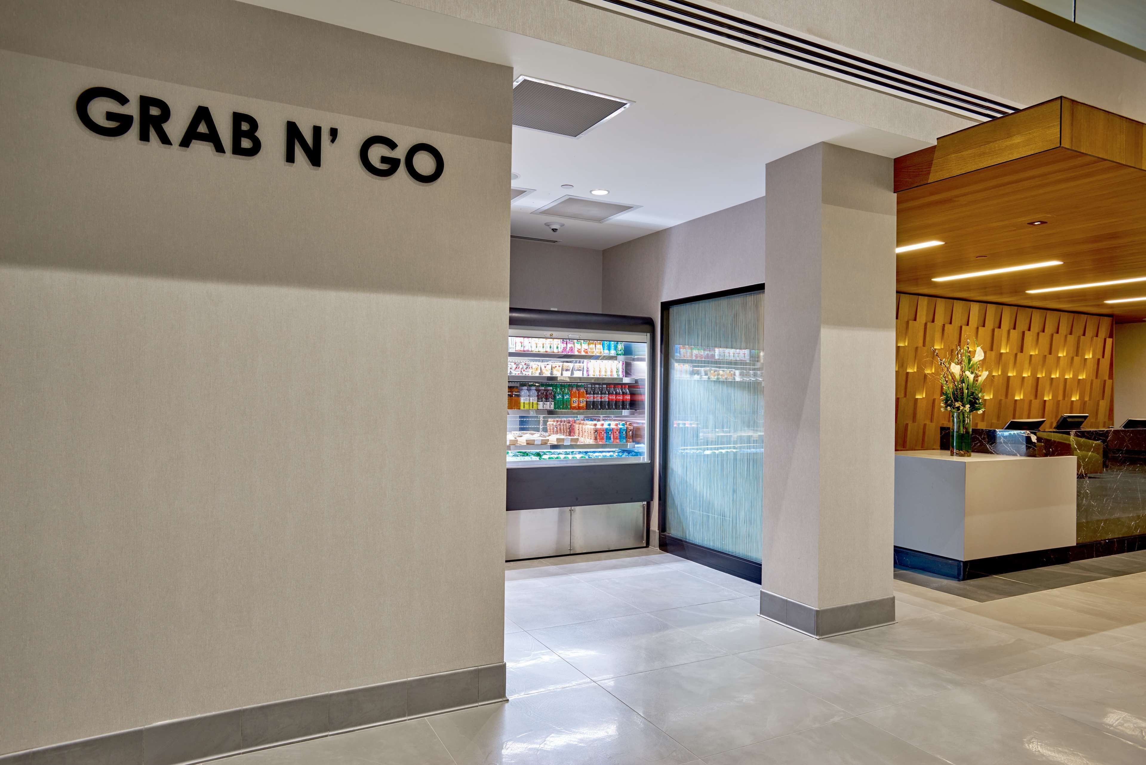 A modern reception area with a 'Grab N' Go' refrigerated section and a wooden reception desk.