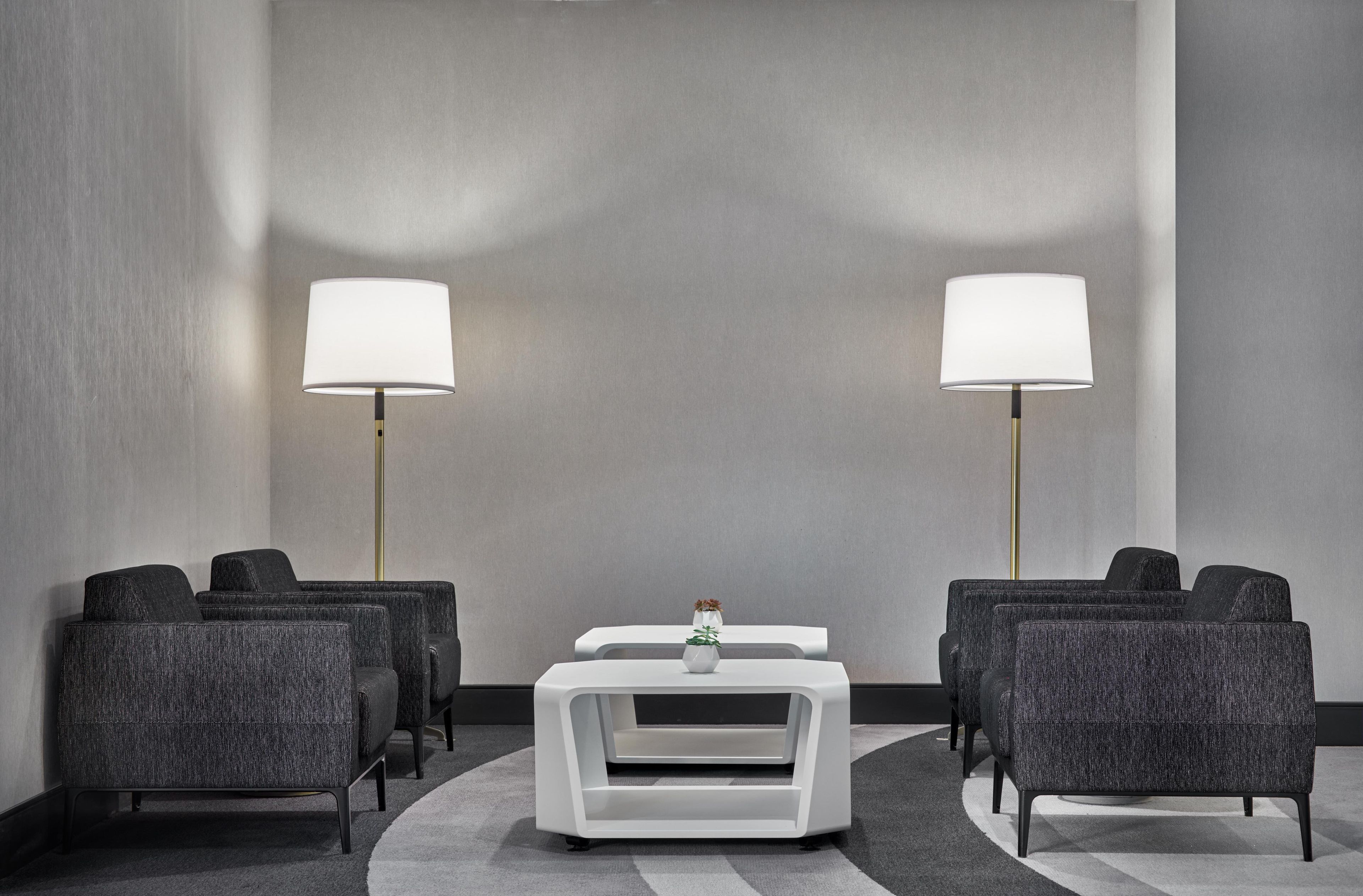 Habitación de hotel con zona de estar, dos lámparas de pie y una mesita con un florero.