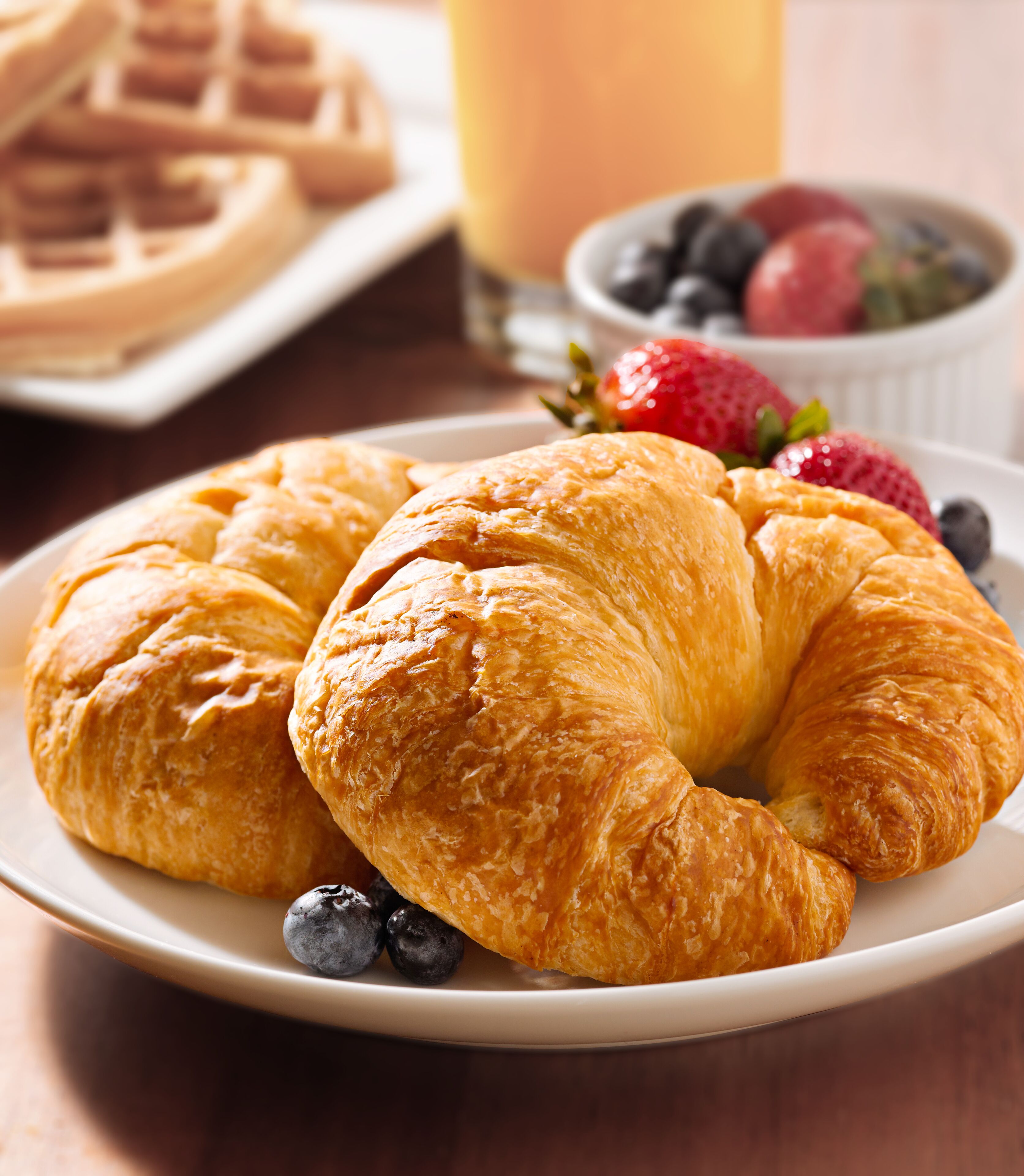 A plate of croissants and blueberries on a table.