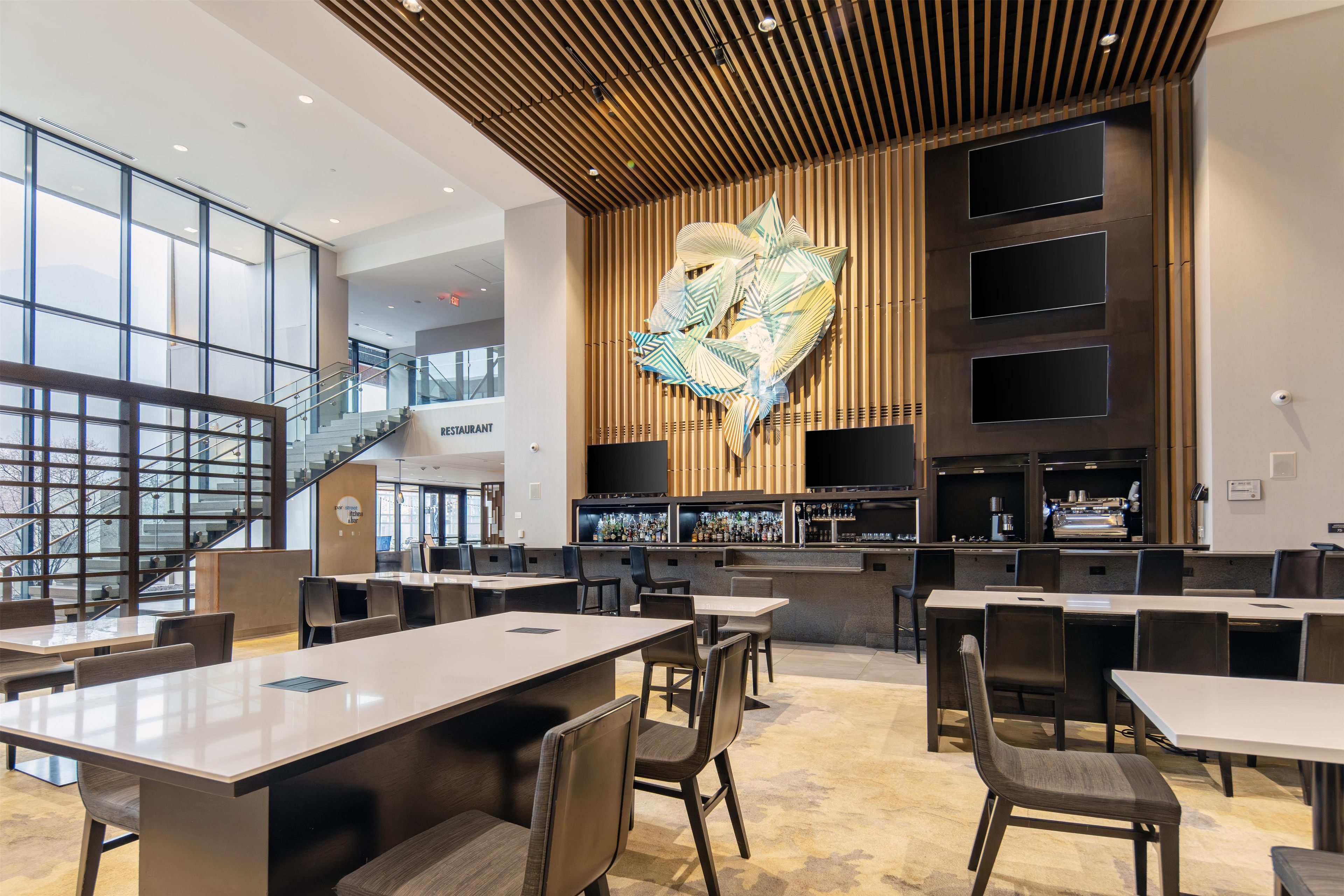 Interior moderno de restaurante com área de bar, disposição de mesas e escadaria para um andar superior.