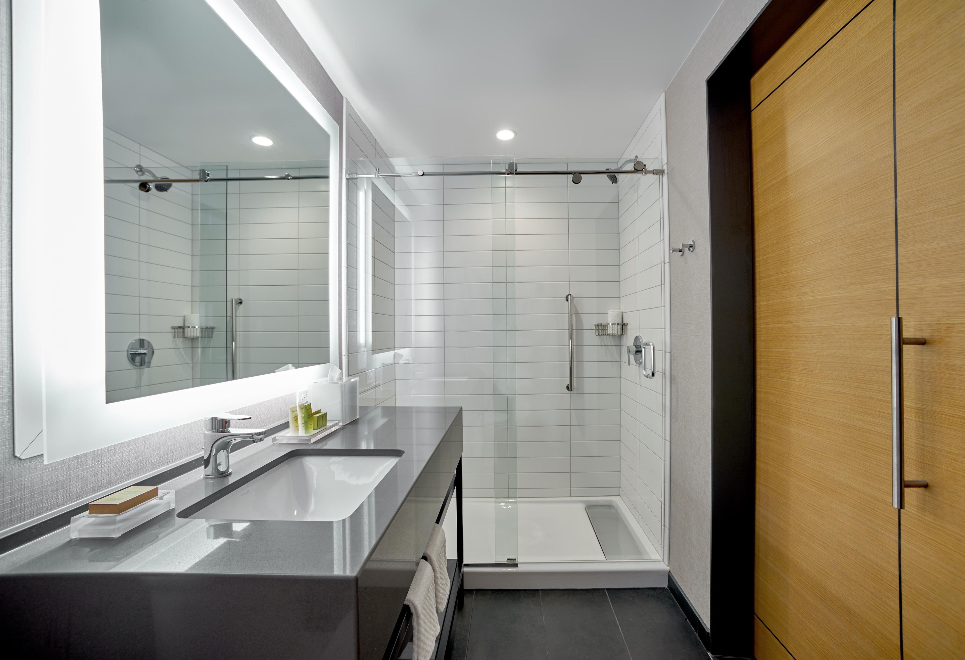 A modern bathroom with a dual sink vanity, a glass shower enclosure, and a wooden wardrobe.
