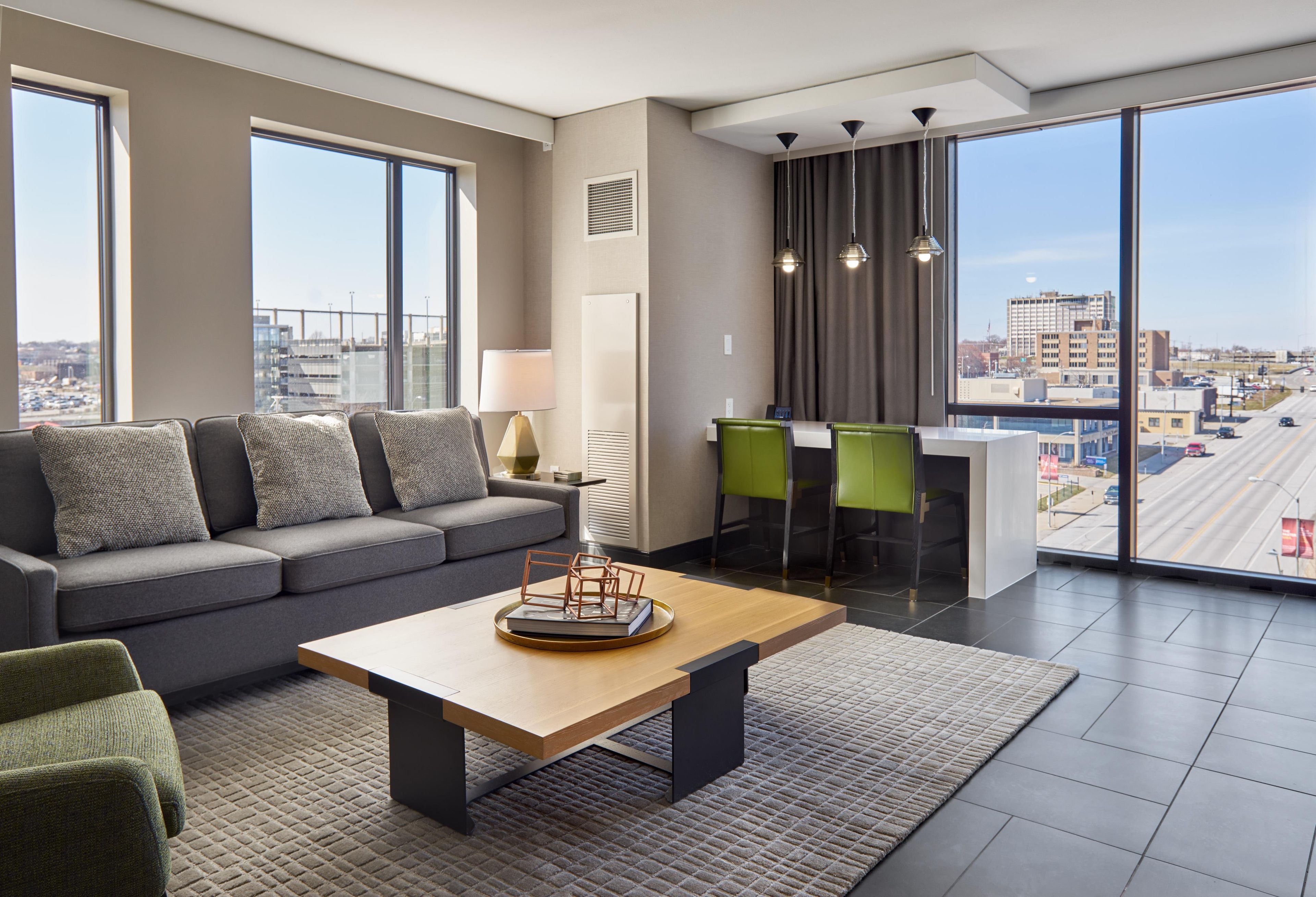 A modern living room with a sofa, a coffee table, and a view of the city through large windows.