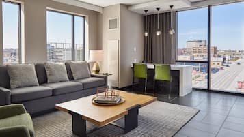 A modern living room with a sofa, a coffee table, and a view of the city through large windows.