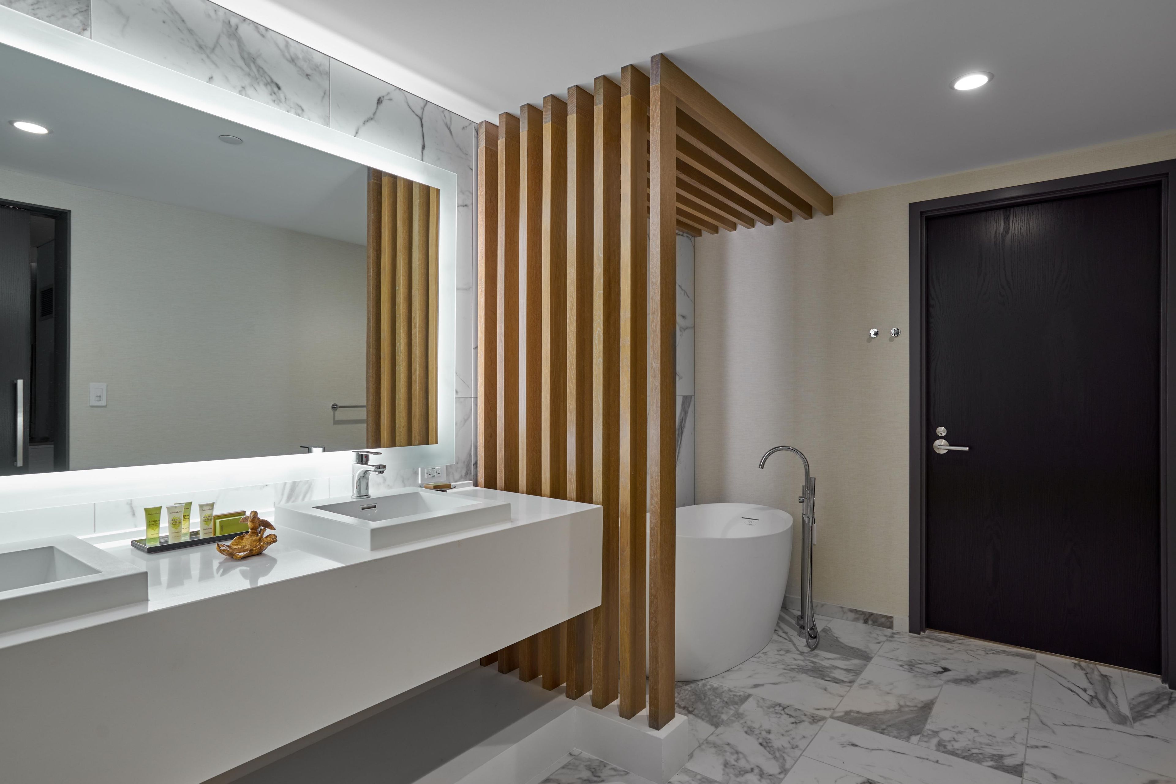 A modern bathroom with two sinks, a large mirror, and a dark door.