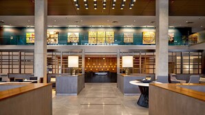 A spacious lobby with a central reception desk, seating areas, and artwork on the walls.