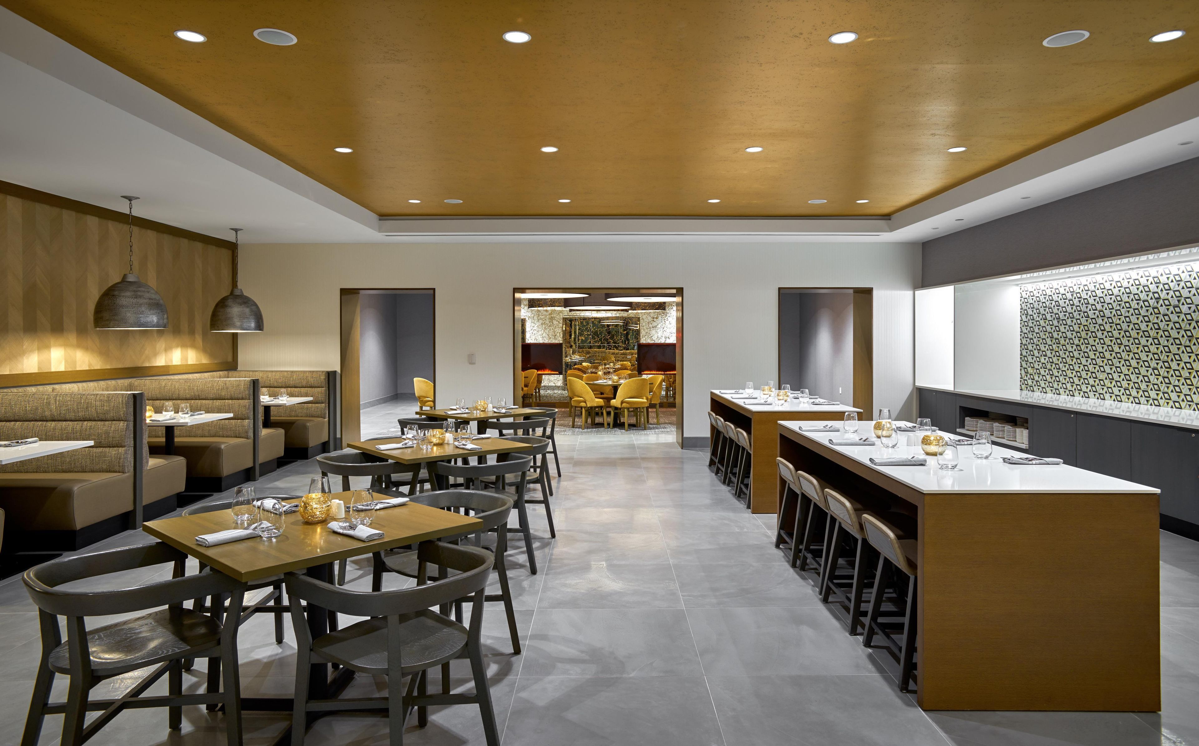 A modern restaurant interior with booths, tables, and a bar area.