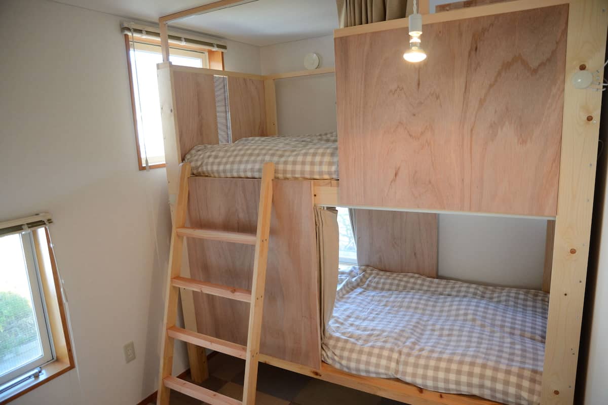 A bunk bed room with a ladder, a window, and a light fixture.