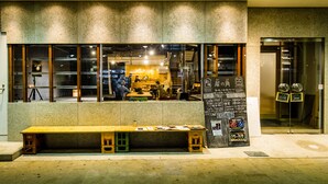Un restaurante con una banca de madera afuera, ventanas grandes y un menú en la pizarra.