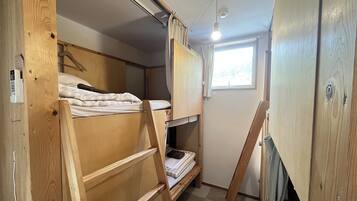 Habitación pequeña con literas, una ventana y una lámpara en el techo.