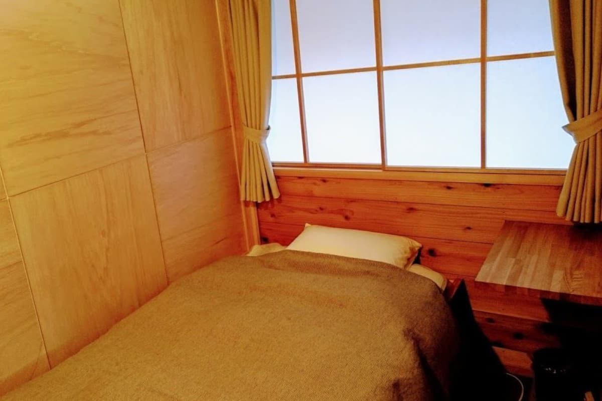 A small room with wooden walls and a window with curtains.