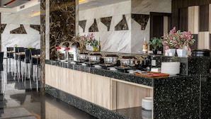 Un moderno vestíbulo de hotel con mostrador de recepción de mármol, zona de estar y plantas decorativas.