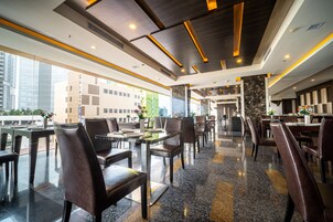 Un restaurante moderno con techos altos, suelos de granito pulido y vistas a la ciudad.