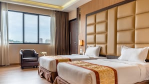 Habitación de hotel con dos camas, una silla, un ventanal grande y vista a la ciudad.