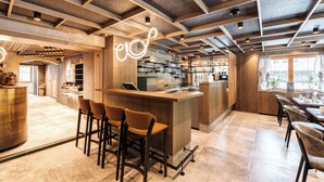 Un espace bar moderne, doté d’un comptoir en bois, de tabourets de bar et d’une sélection bien fournie de boissons alcoolisées.