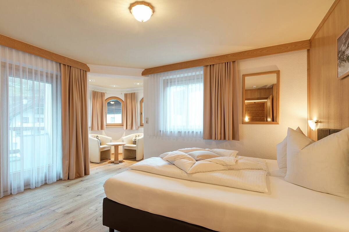 A hotel room with a large bed, a desk, and a chair.