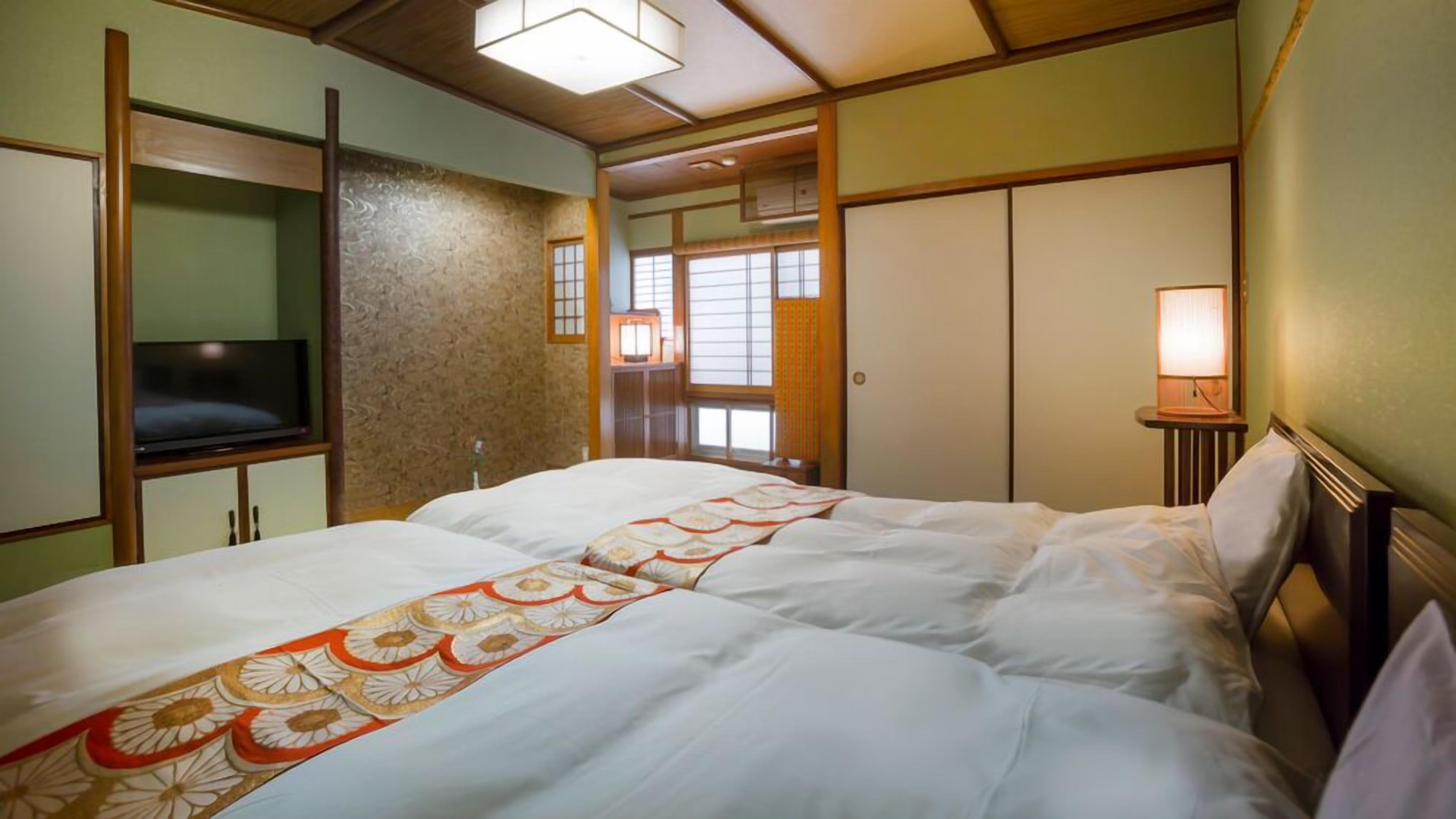 Una habitación de hotel con cama, televisión, lámpara de noche y ventana con persianas.