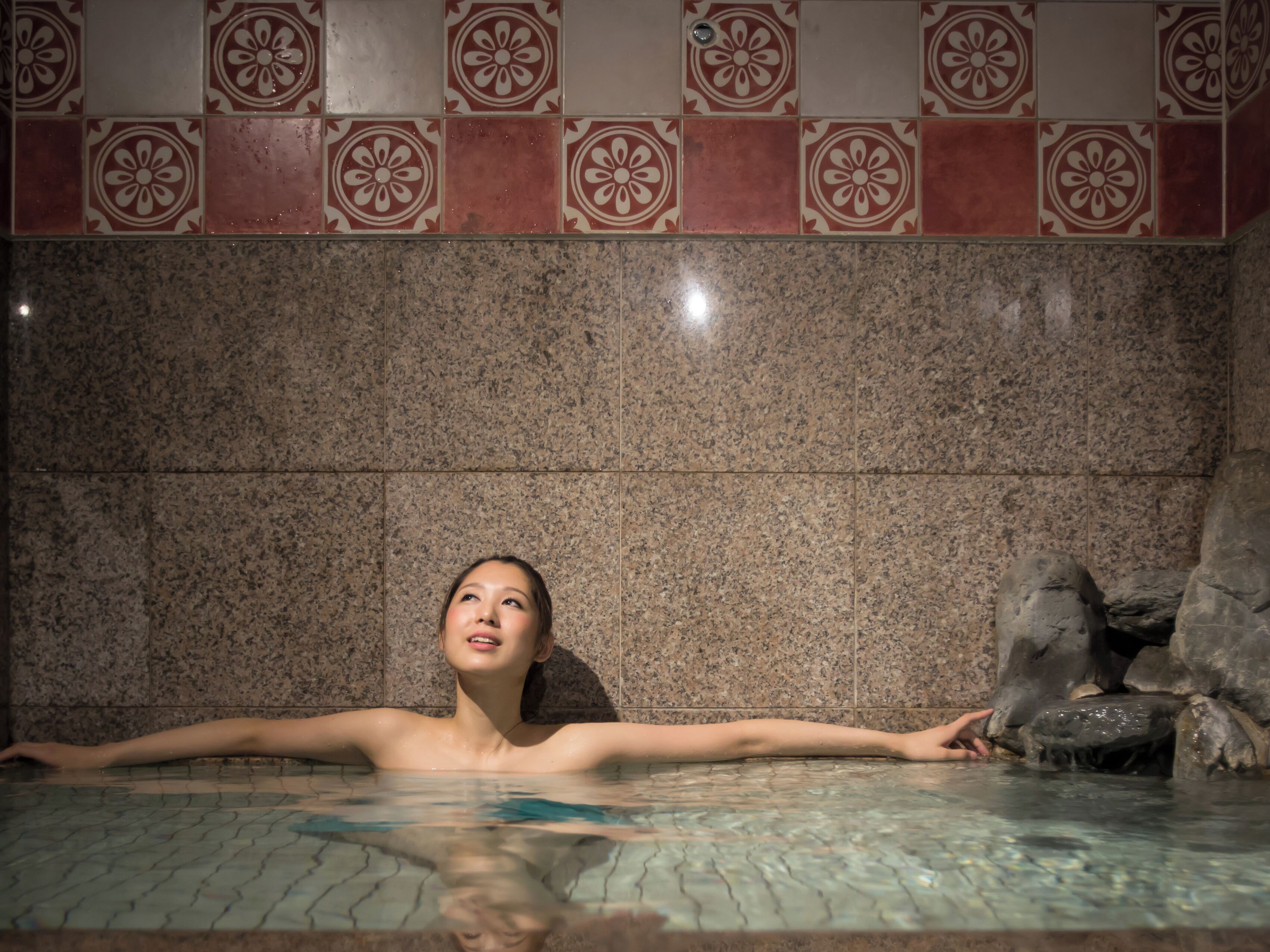 A person in a hot tub with a tiled wall behind them.