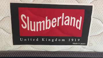 Un letrero con el texto 'Slumberland United Kingdom 1919 Made in Japan' sobre una pared con textura.