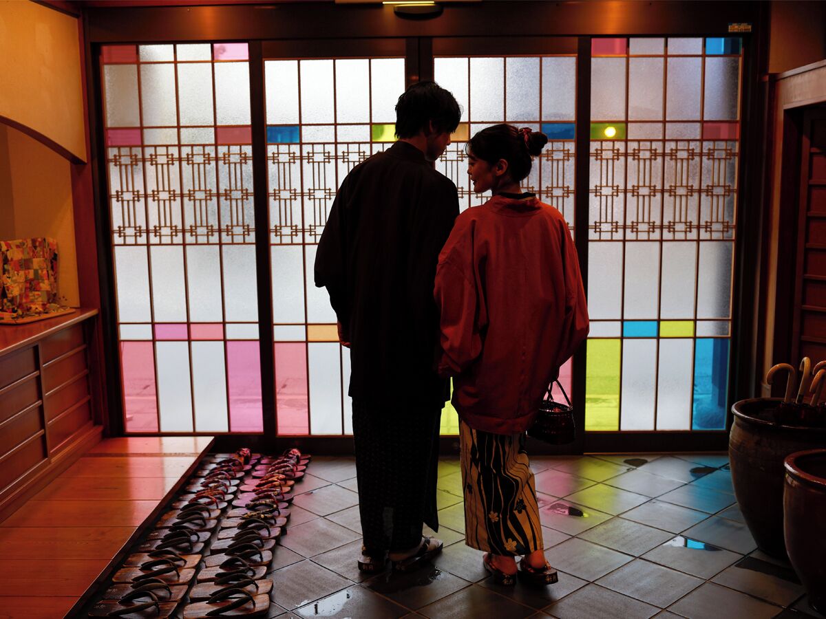 A traditional Japanese interior with a sliding door, a tiled floor, and a display of shoes.