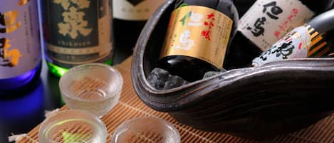 Un juego tradicional japonés de sake con botellas y copas pequeñas sobre una estera de bambú.