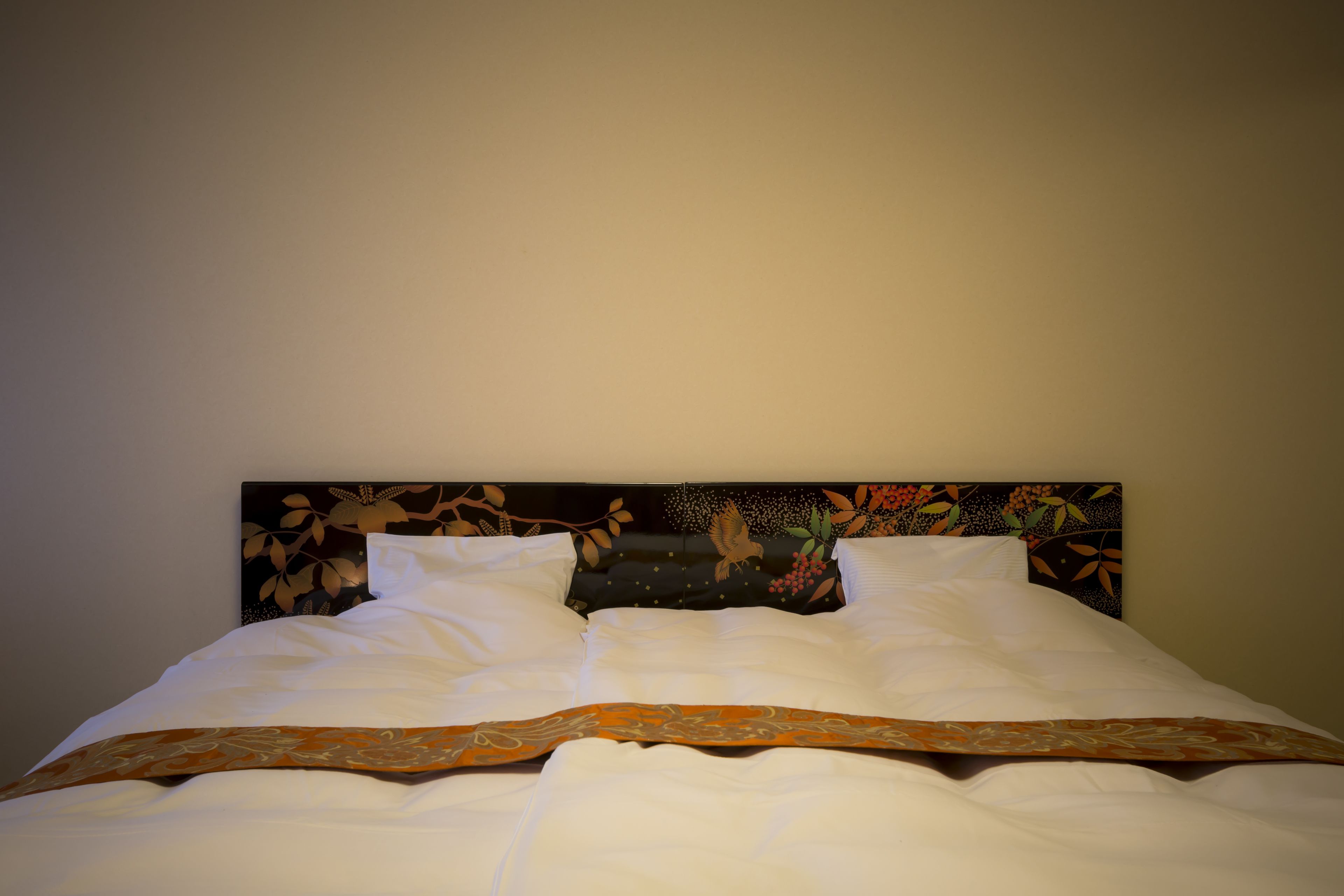 A neatly made bed with white linens and a decorative headboard.