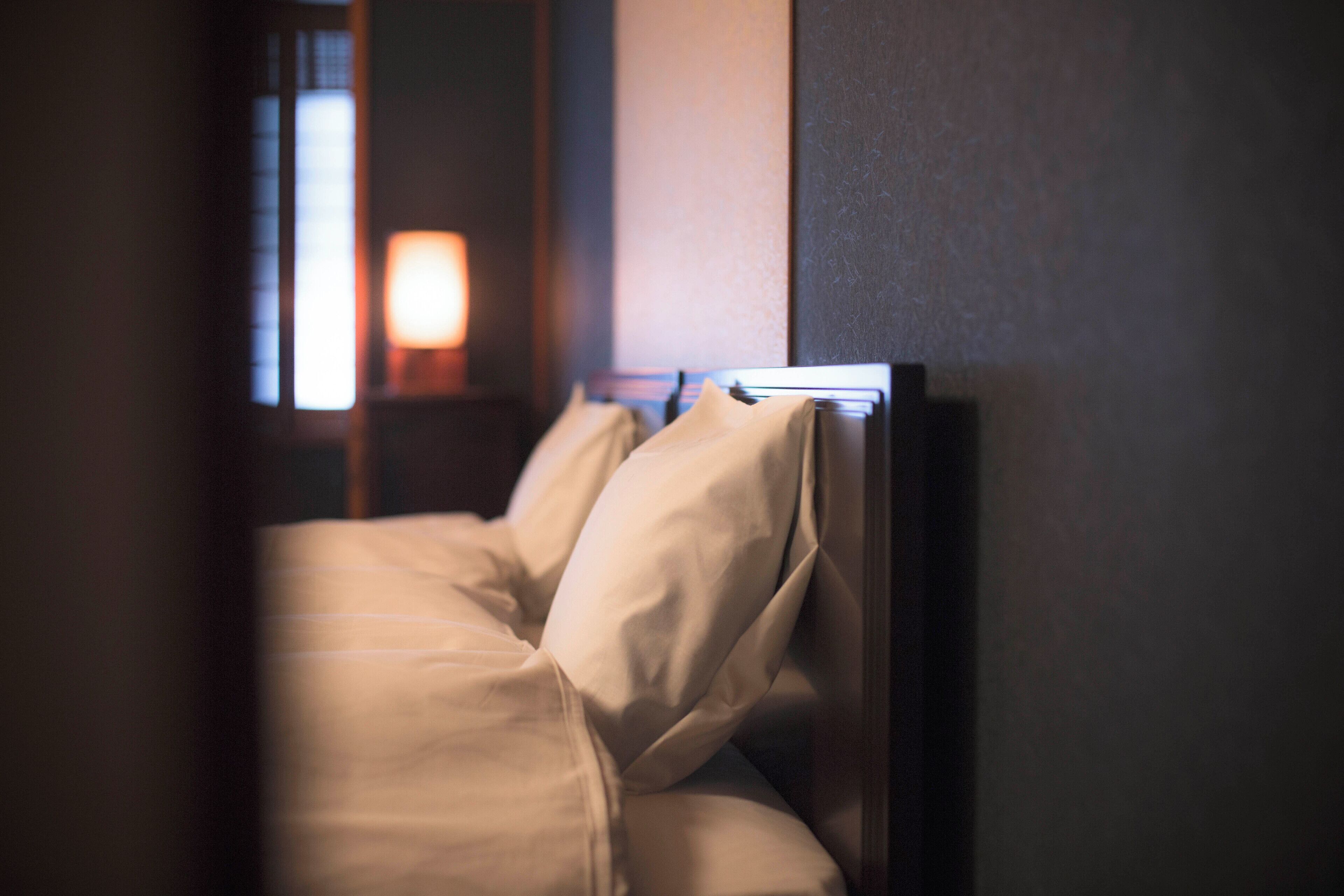 A hotel room with a bed, a nightstand, and a lamp.