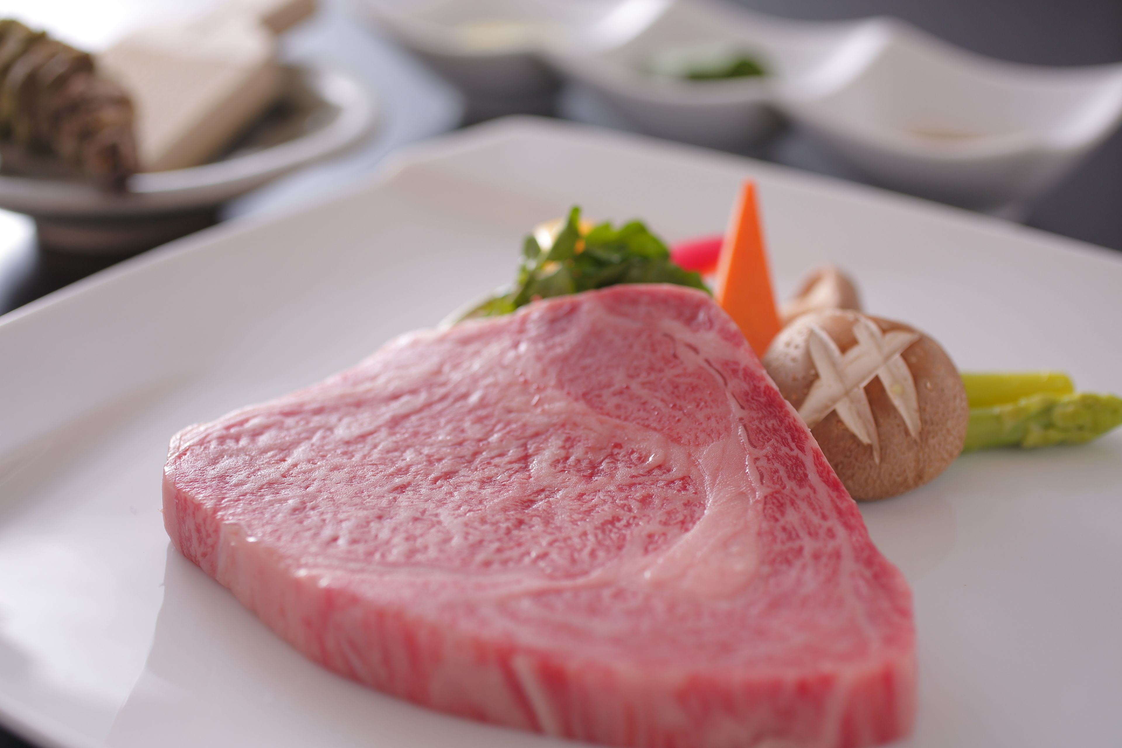 A plate with a slice of meat, asparagus, and a mushroom.